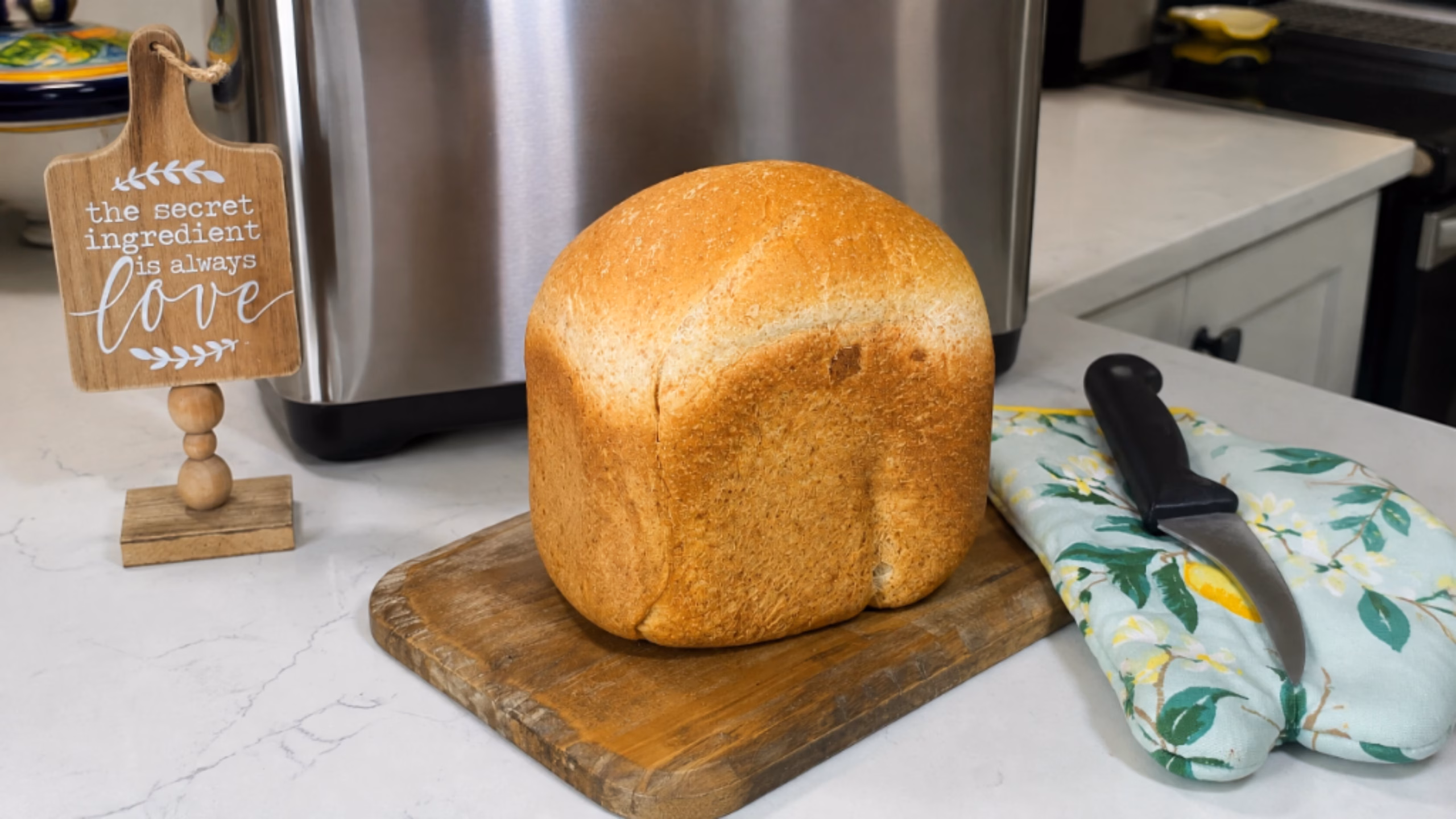 Homemade bread machine maple wheat bread with three slices on a wooden cutting board.