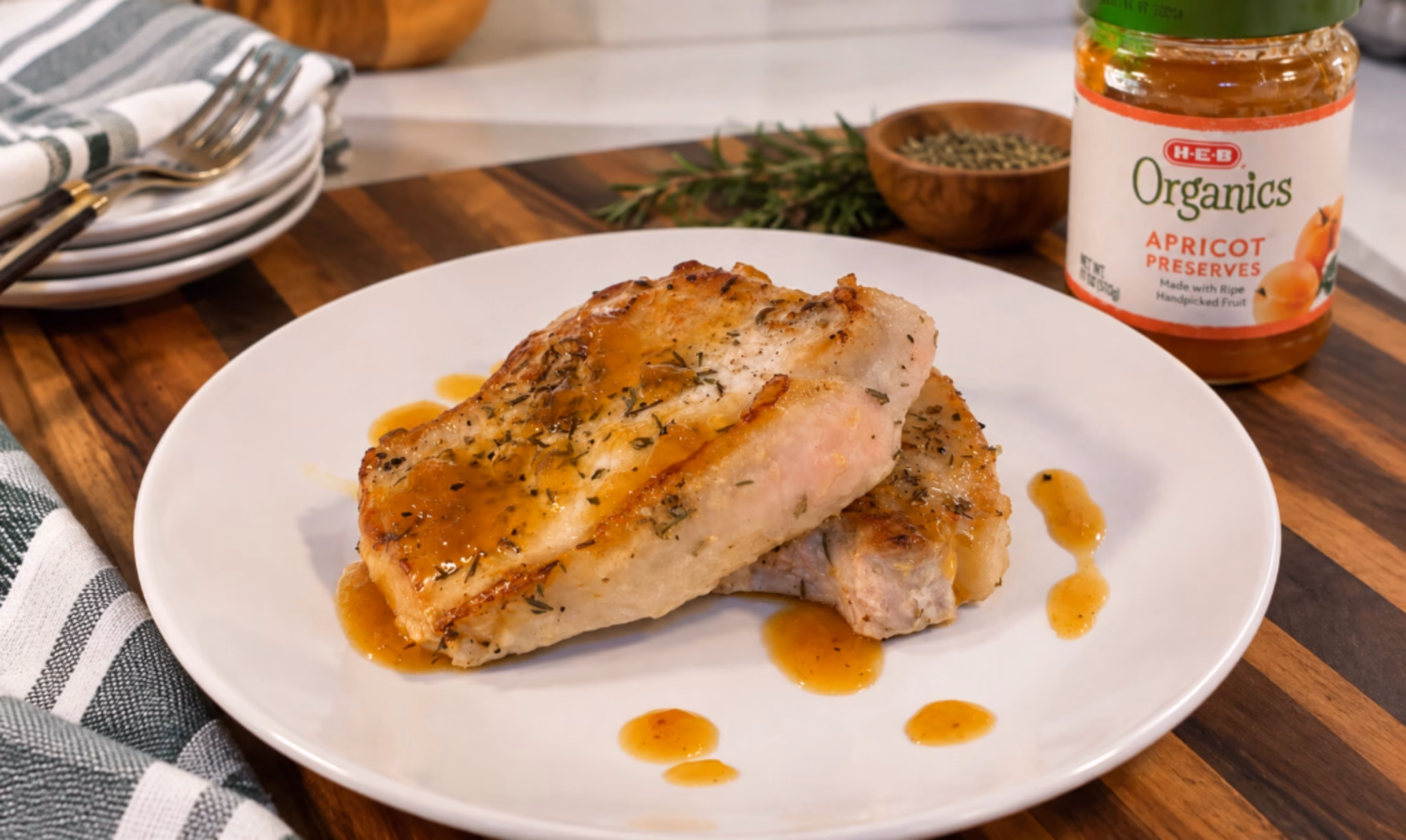 pork chops with apricot glaze on a white plate with a jar of apricot preserves