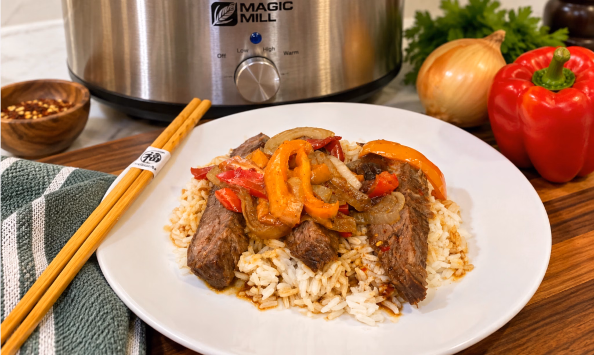 pepper steak and onions on a white plate with chopsticks with a slow cooker in the background