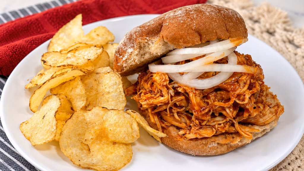 Instant Pot pulled BBQ chicken sandwich with pickled onion and potato chips.
