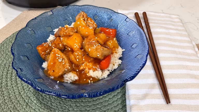 Instant Pot sweet and sour pork with pineapple, bell peppers, onion, and jasmine rice in a white bowl.