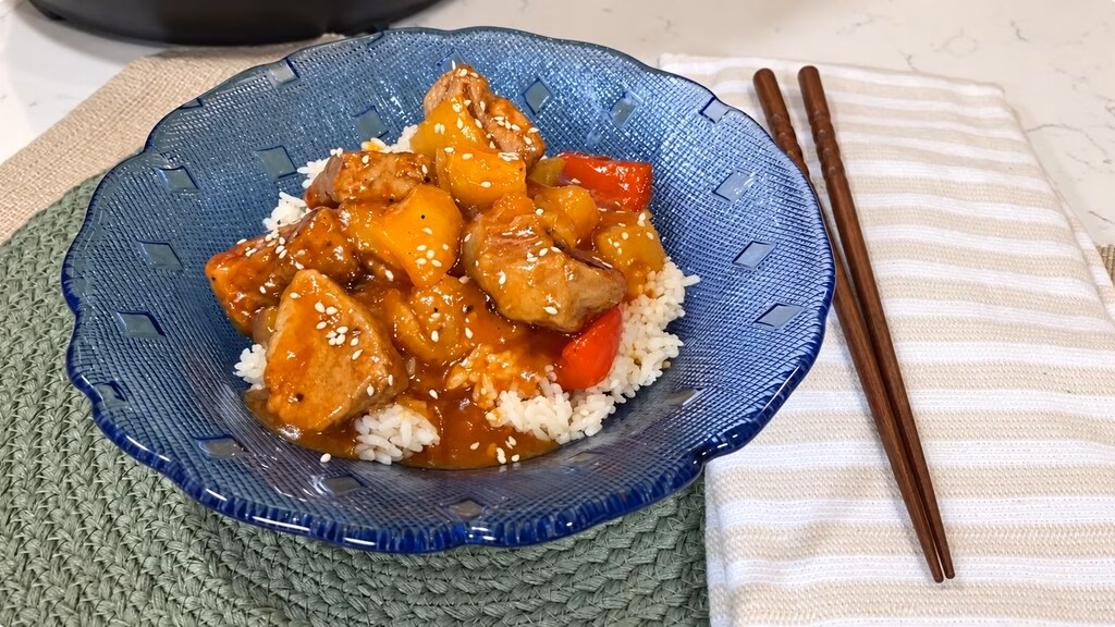 Instant Pot sweet and sour pork with pineapple, bell peppers, onion, and jasmine rice in a white bowl.